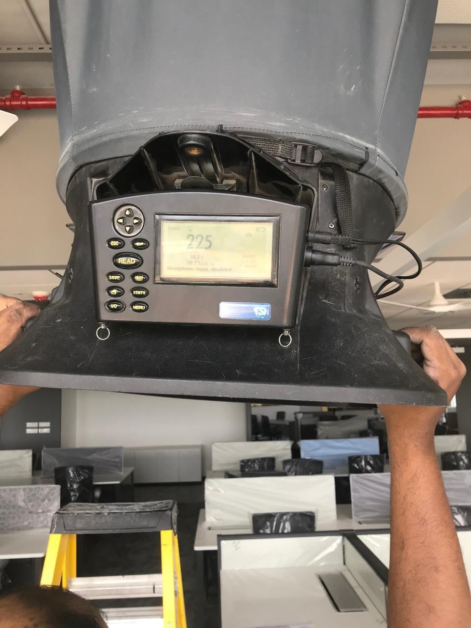 Technician performing air balancing on an HVAC duct outlet with a flow measurement instrument